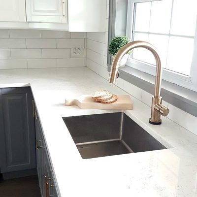 Can you mix metals in a kitchen? Here is how we mixed a stainless steel sink with a brushed gold kitchen faucet by Delta (the Trinsic). Result: Gorgeous! See the rest of our gray and white kitchen, and get all of the design sources, in the post!