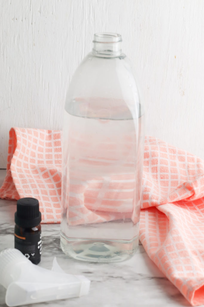 clear bottle next to a cloth and essential oil.