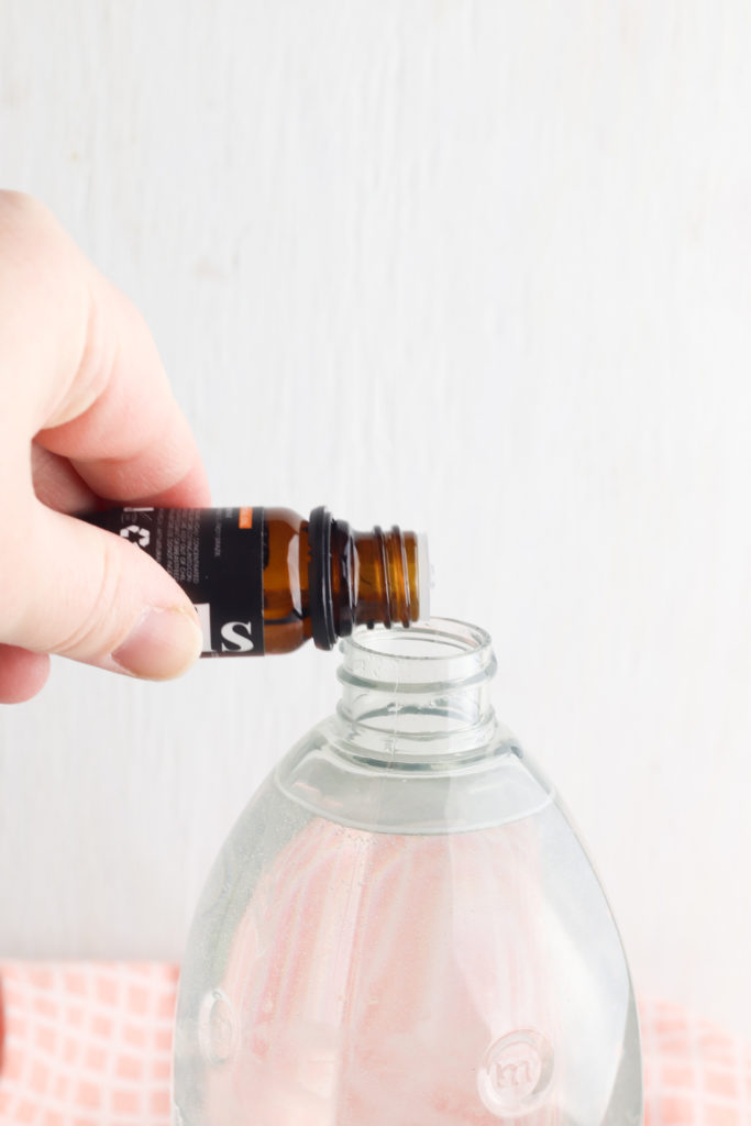 Adding essential oil to the diy class cleaner in a plastic bottle.