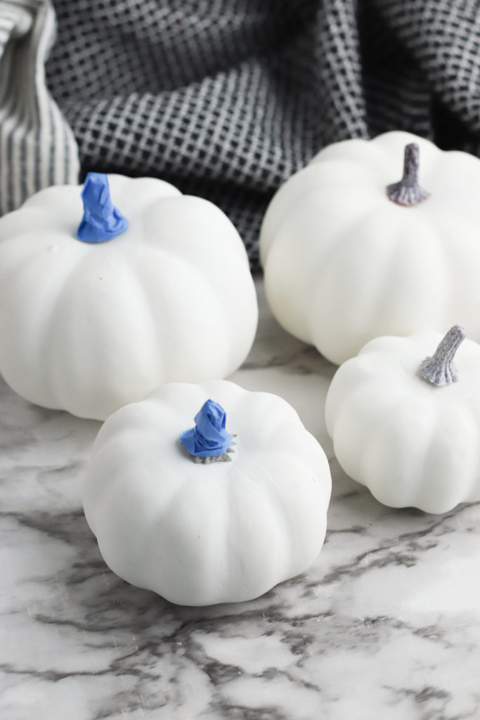 White pumpkins with blue masking tape covering the stem.